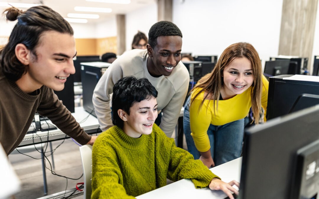 Young diverse students huddling around a computer in the computer lab