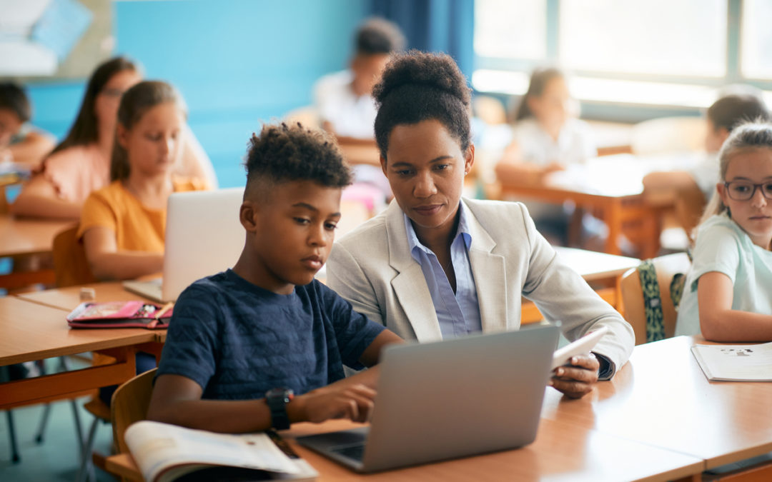 Teacher adapting learning for male K-12 student in computer classroom
